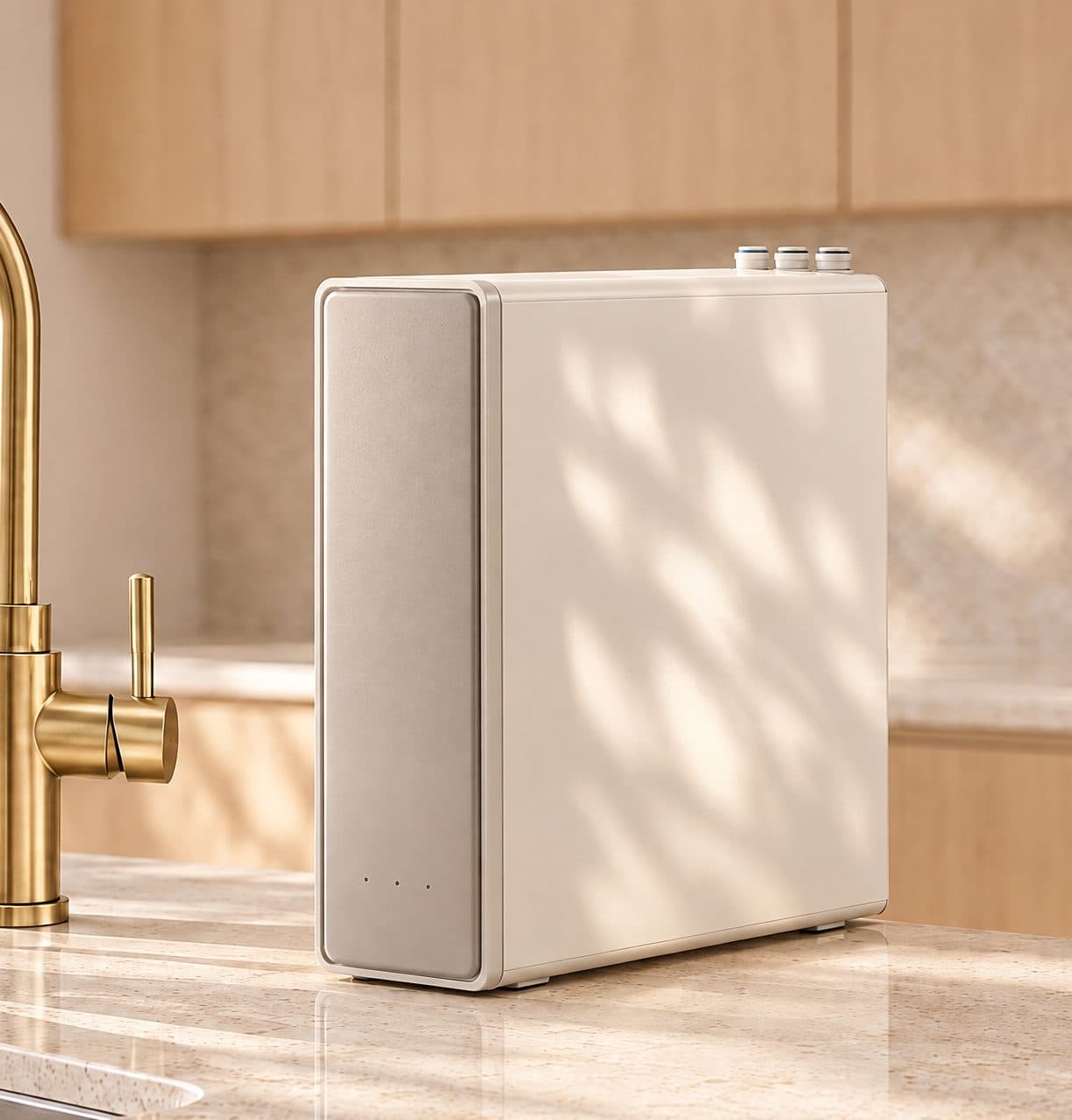 Equipo de ósmosis inversa blanco sobre la encimera de una cocina, junto a un grifo dorado que llena un vaso de agua